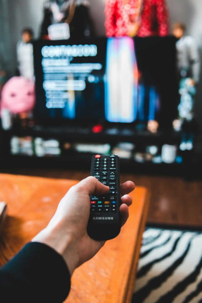 a person controlling their TV with a back remote control.