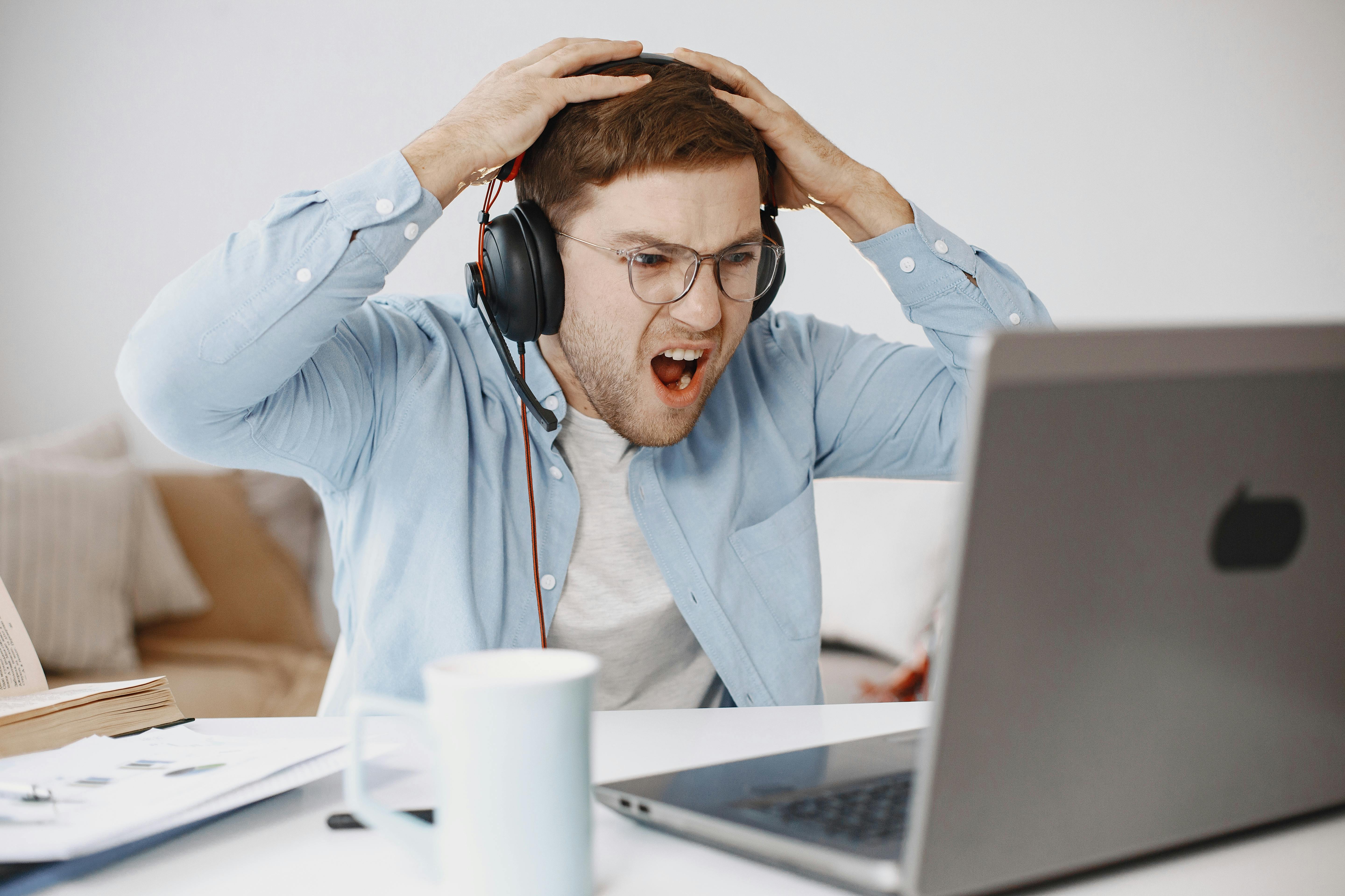 Young man frustrated with his gaming laptop running slow